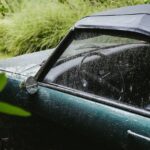 a wet car parked beside the grass