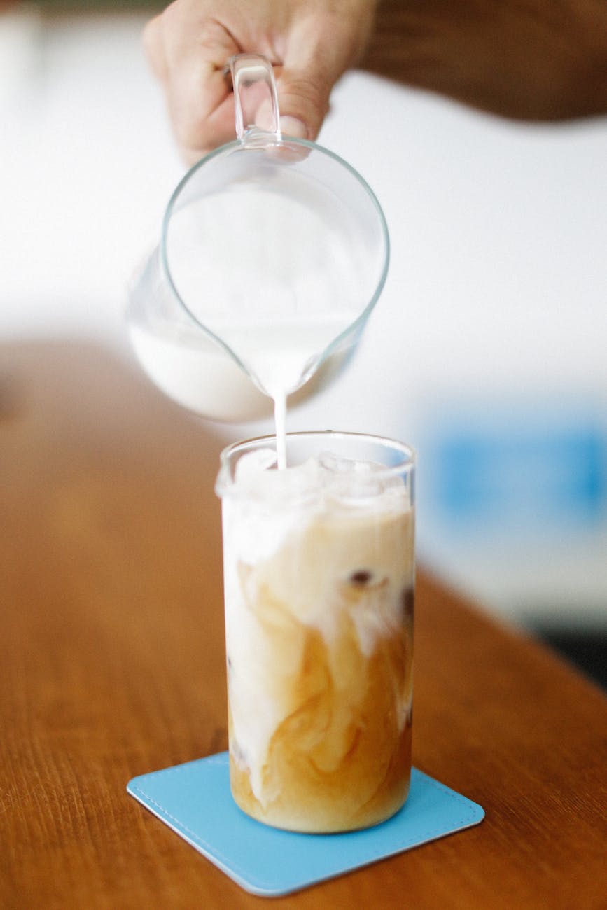 hand pouring milk into coffee
