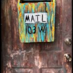 multi coloured wooden mailbox mounted on door