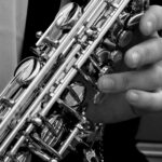 person holding saxophone in gray scale photography