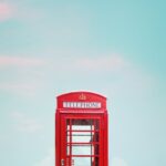 photo of red telephone booth under blue sky