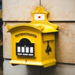 yellow postbriefkasten floating mailbox on brown concrete wall