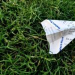 receipt folded into paper plane on grass